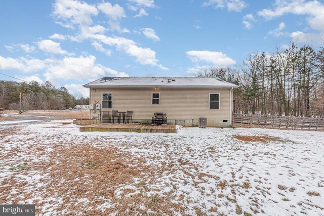 snow covered house with a deck, central AC, and fence