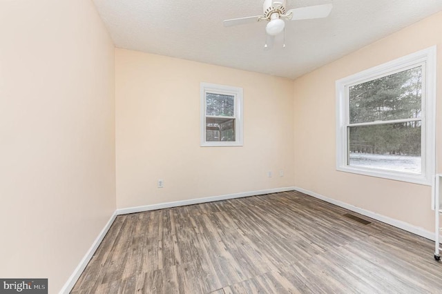 spare room featuring baseboards, visible vents, ceiling fan, wood finished floors, and a textured ceiling