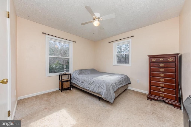 bedroom with baseboards, a textured ceiling, and light colored carpet