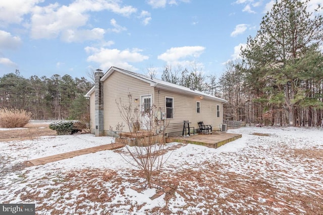 snow covered property featuring a chimney, cooling unit, and a wooden deck