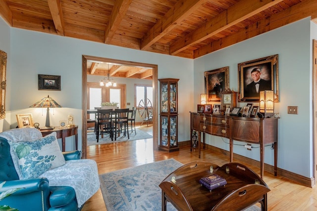 living area featuring wood finished floors, baseboards, an inviting chandelier, wooden ceiling, and beamed ceiling