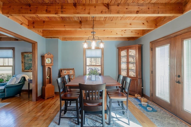 dining area with beamed ceiling, plenty of natural light, a chandelier, and light wood finished floors