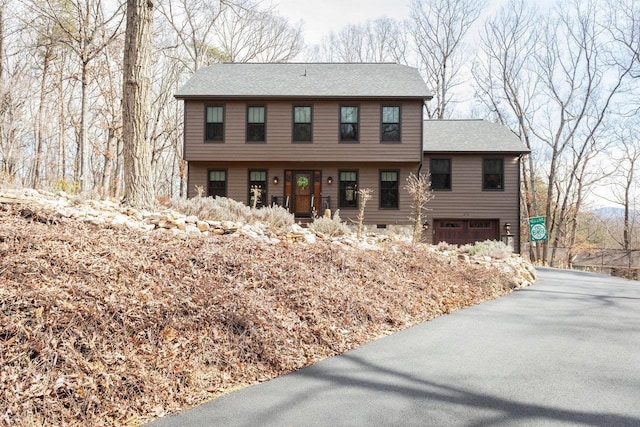 colonial home featuring aphalt driveway, a garage, and a shingled roof