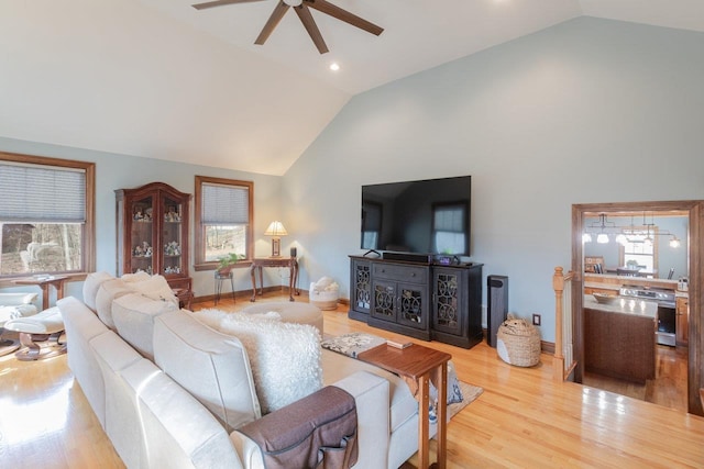 living room featuring baseboards, high vaulted ceiling, wood finished floors, and a ceiling fan