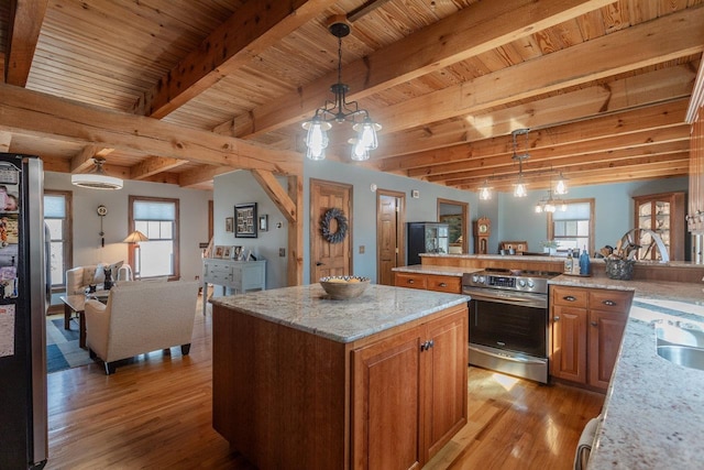 kitchen featuring light stone counters, a kitchen island, stainless steel appliances, light wood-style floors, and brown cabinets