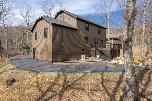 rear view of house with a wooden deck, stairs, and central AC