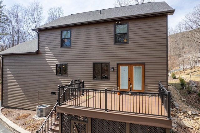 rear view of house with a deck, cooling unit, french doors, and roof with shingles