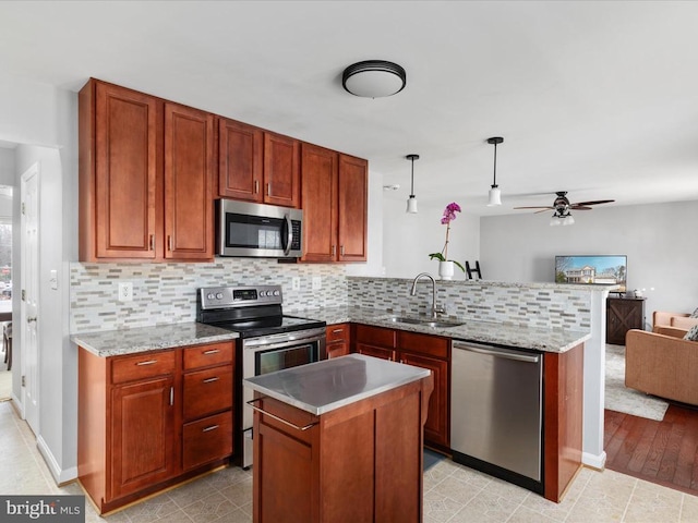 kitchen featuring a sink, tasteful backsplash, open floor plan, appliances with stainless steel finishes, and a peninsula