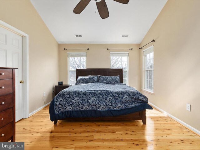 bedroom featuring vaulted ceiling, multiple windows, visible vents, and light wood-type flooring