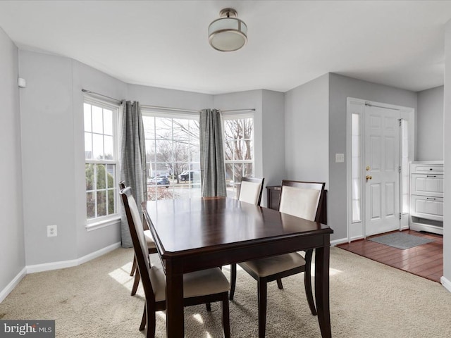 dining space with baseboards and light colored carpet