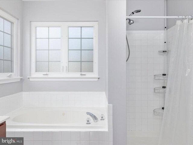 full bathroom featuring a garden tub, vanity, and a tile shower