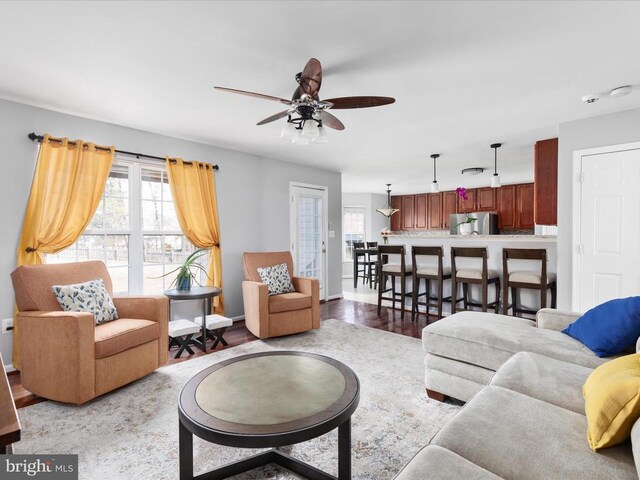 living area featuring baseboards, a ceiling fan, and wood finished floors