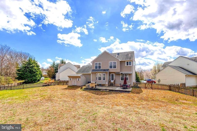 back of house with entry steps, a fenced backyard, a lawn, and a patio area