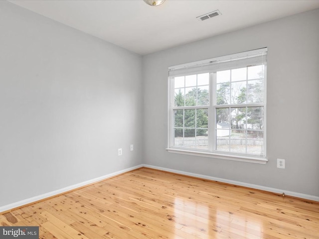 spare room featuring visible vents, baseboards, and hardwood / wood-style flooring