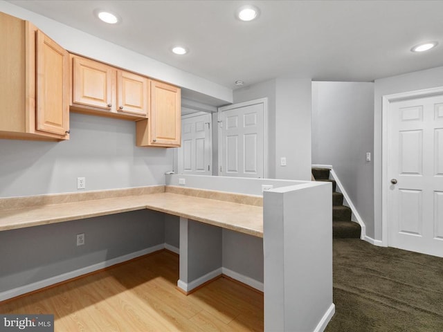 kitchen with recessed lighting, light brown cabinetry, built in desk, and light countertops