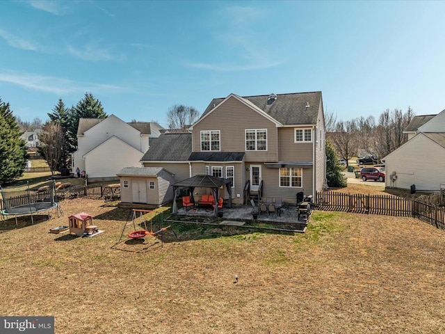 back of house featuring a trampoline, a lawn, and a patio area