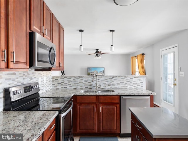 kitchen featuring a sink, decorative light fixtures, tasteful backsplash, appliances with stainless steel finishes, and a peninsula