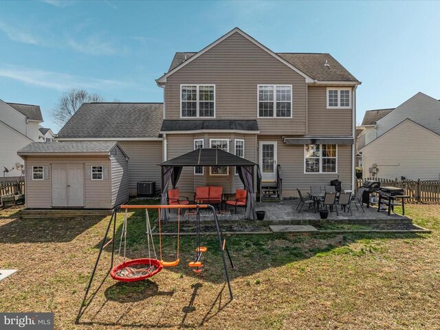 rear view of property featuring central AC unit, an outdoor structure, a storage unit, a patio area, and a lawn