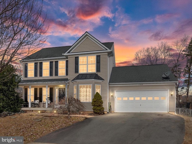 view of front of house with driveway, an attached garage, and a shingled roof