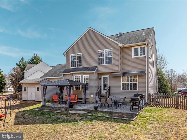 rear view of house featuring entry steps, fence, a patio area, and a lawn