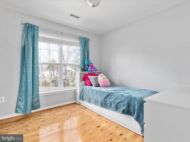 bedroom featuring baseboards, visible vents, and wood-type flooring