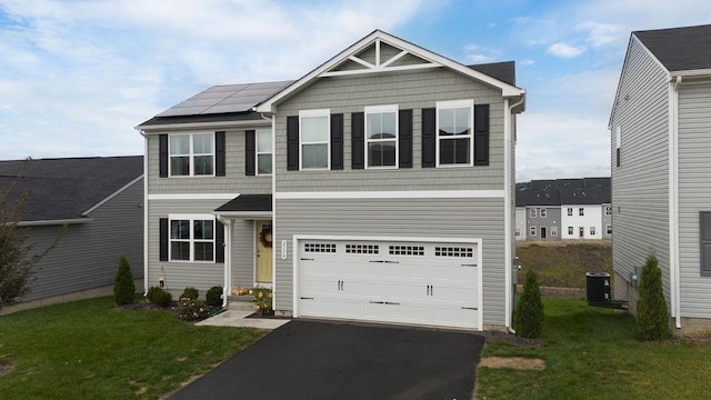 view of front of home with a garage, a front yard, central air condition unit, and solar panels