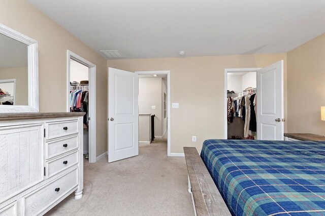 bedroom with a walk in closet, light colored carpet, and a closet