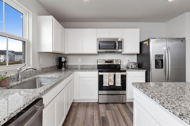 kitchen with appliances with stainless steel finishes, sink, white cabinets, and light stone counters