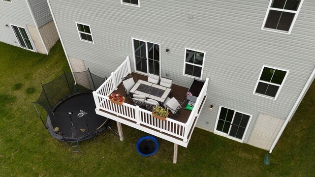 rear view of property with a yard and a trampoline