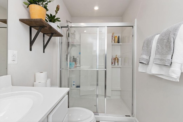 bathroom featuring vanity, an enclosed shower, and toilet