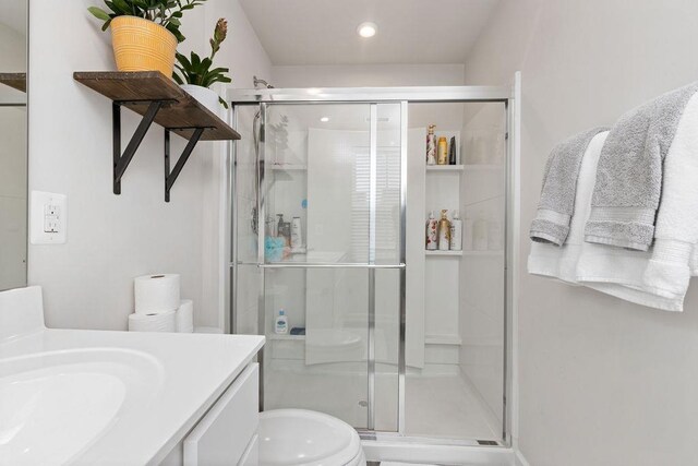 bathroom featuring vanity, an enclosed shower, and toilet