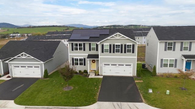 view of front of home with a garage, a mountain view, and solar panels