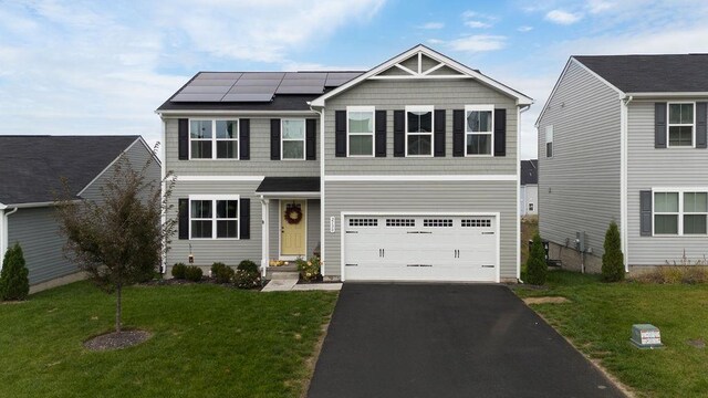 view of front of home with a garage, a front yard, and solar panels