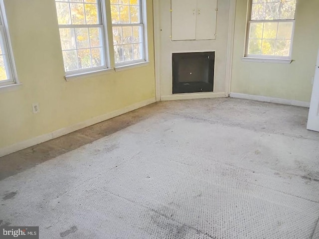 unfurnished living room featuring light colored carpet, a healthy amount of sunlight, and a fireplace