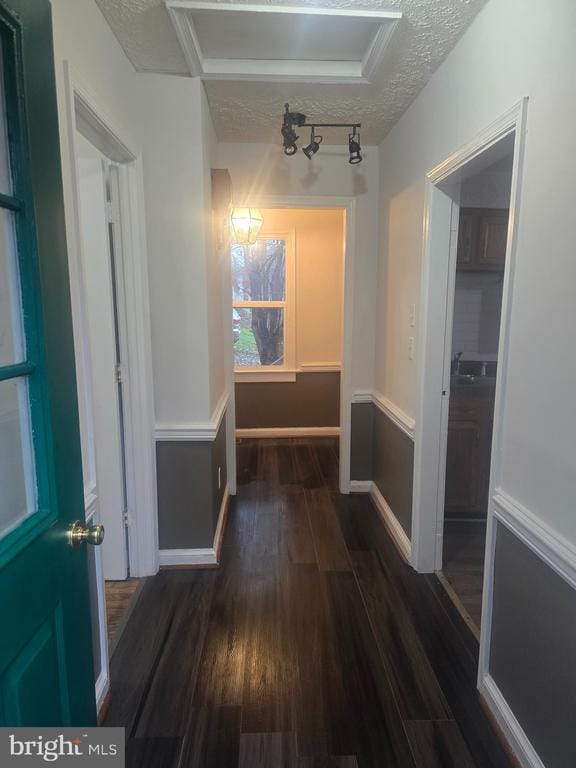 corridor featuring dark wood-type flooring and a textured ceiling