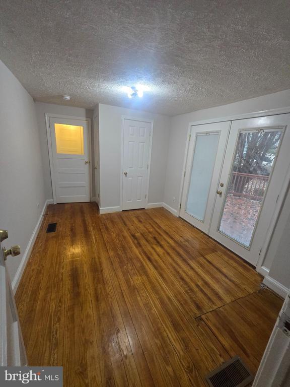 spare room with hardwood / wood-style flooring, a textured ceiling, and french doors