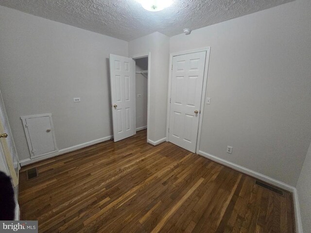 unfurnished bedroom featuring dark wood-type flooring, a textured ceiling, and a closet