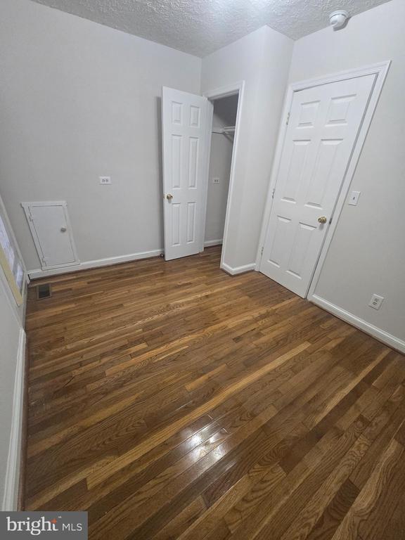 unfurnished bedroom with dark hardwood / wood-style floors, a textured ceiling, and a closet