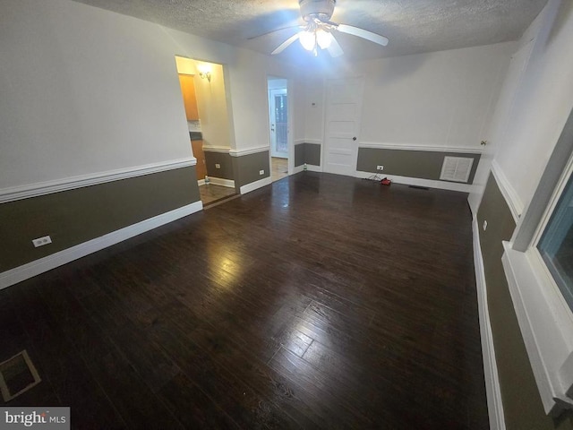 empty room featuring ceiling fan, dark wood-type flooring, and a textured ceiling