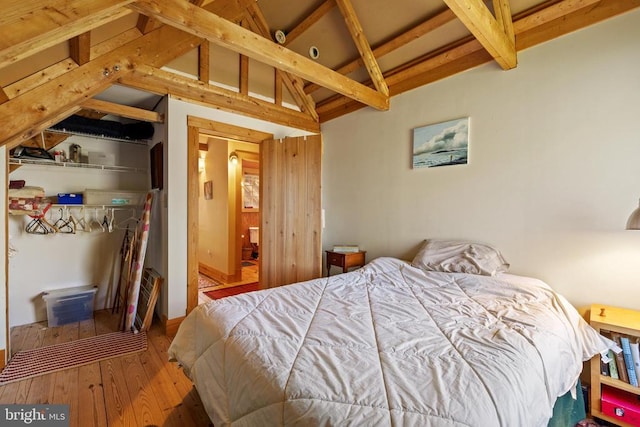 bedroom featuring lofted ceiling with beams and hardwood / wood-style flooring