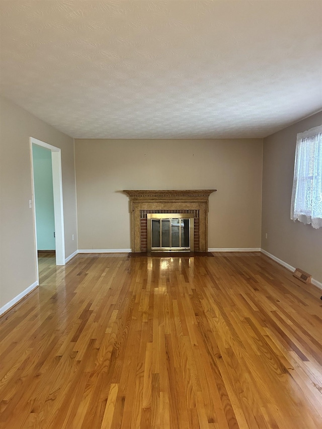 unfurnished living room with a brick fireplace and hardwood / wood-style flooring