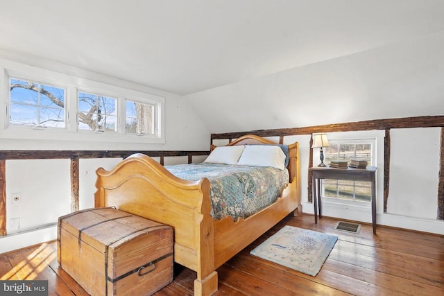 bedroom featuring multiple windows, wood-type flooring, and lofted ceiling