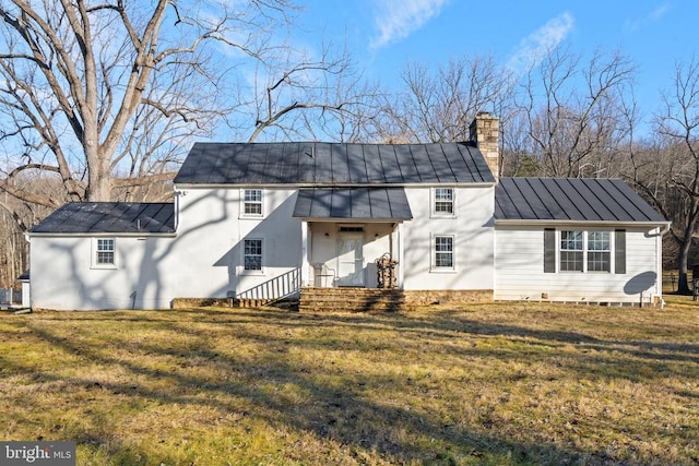 back of house with metal roof, a lawn, a chimney, and a standing seam roof