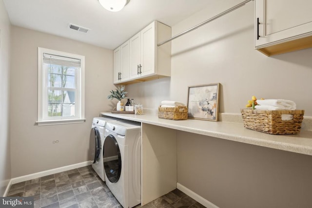 clothes washing area with cabinet space, visible vents, baseboards, and separate washer and dryer