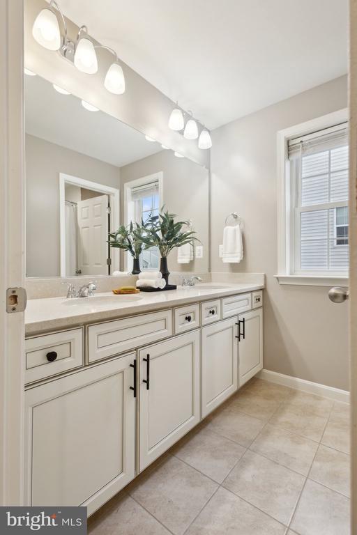 full bath featuring tile patterned flooring, a sink, baseboards, and double vanity