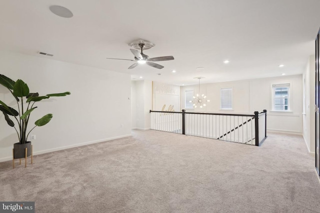 carpeted empty room featuring visible vents, baseboards, recessed lighting, and ceiling fan with notable chandelier