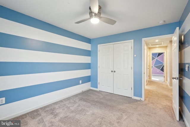 unfurnished bedroom with carpet floors, a closet, baseboards, and ceiling fan