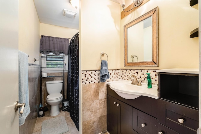 full bath with toilet, wainscoting, vanity, and tile walls