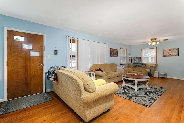 living room featuring a ceiling fan, baseboards, and wood finished floors