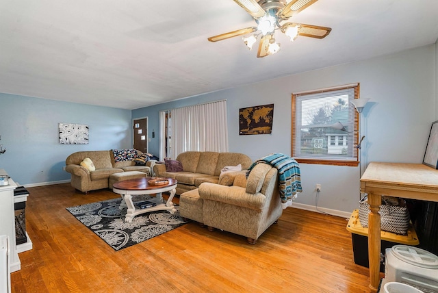 living area with baseboards, ceiling fan, and light wood finished floors